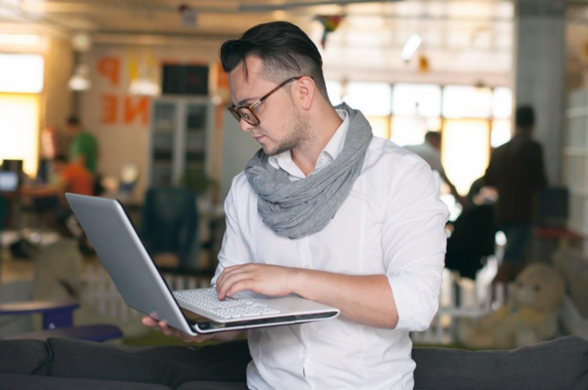 Student working through investment analysis on laptop with notes and research materials